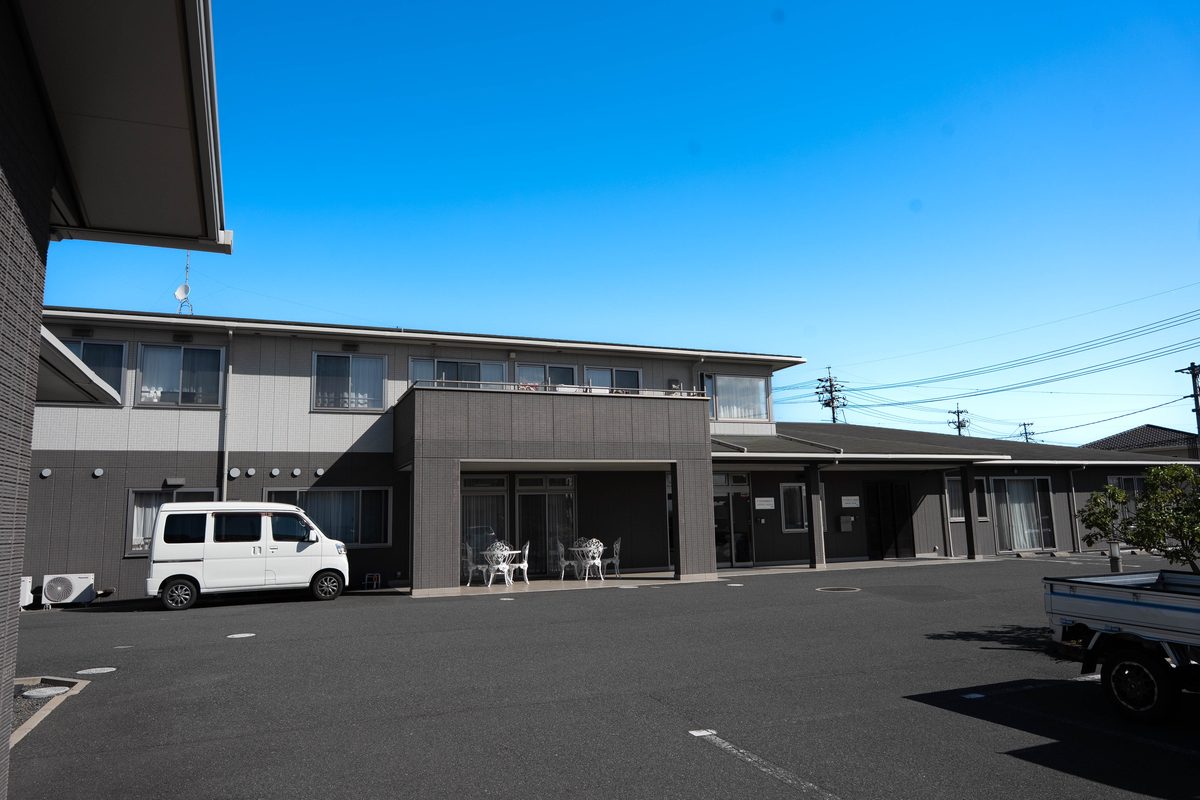こはる日和の建物と、駐車場に停まる送迎車